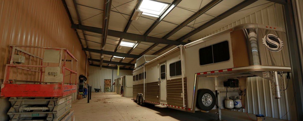 parked horse trailer and stables on side of horse arena facility